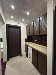 a kitchen with brown cabinets and a black door at فندق اوتاد المتحدة عبالله الخياط in Mecca