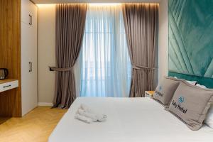 a bedroom with a large white bed with curtains at Hotel Saly in Durrës