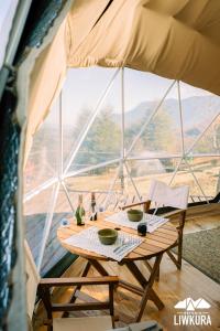 une table et des chaises dans une tente avec une grande fenêtre dans l'établissement Agroglamping REFUGIO LIWKURA, à Caburgua