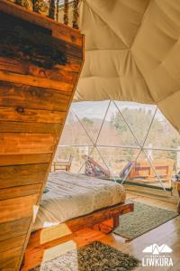 un letto in una camera con una grande finestra di Agroglamping REFUGIO LIWKURA a Caburgua