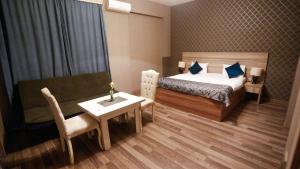 Nemi Museum Hotel Baku في باكو: غرفة نوم بسرير وطاولة واريكة
