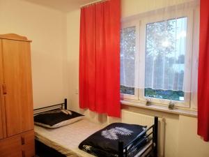 sypialnia z łóżkiem i oknem z czerwonymi zasłonami w obiekcie Ewa Dom w Warszawie