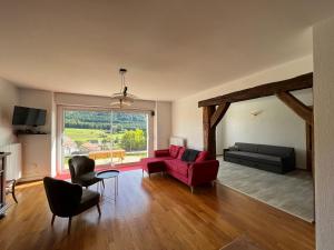 sala de estar con sofá rojo y silla roja en Le Crozet, en Arçon