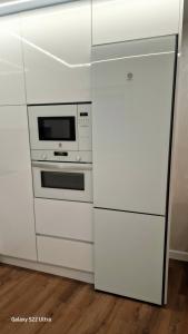 eine weiße Küche mit einer Mikrowelle und einem Kühlschrank in der Unterkunft Ventana a Santa María in Burgos