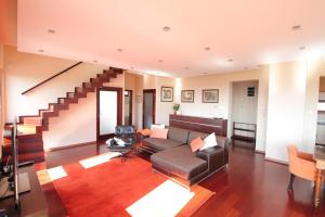 uma sala de estar com um sofá e escadas em August Panorama Apartman em Vác