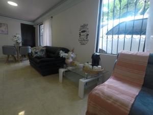 ein Wohnzimmer mit einem Sofa und einem Tisch in der Unterkunft CASA HOTEL FLOR DEL VALLE in Cali