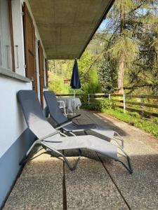 2 Liegestühle und ein Sonnenschirm auf der Veranda in der Unterkunft Friedmatte Breathtaking View in Beatenberg