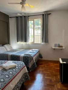 a hotel room with two beds and a window at Pousada Solar Teresa in Petrópolis