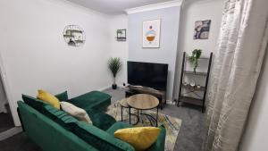 a living room with a green couch and a table at Saxon Street House in Gillingham