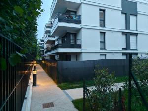 a white building with a fence next to a sidewalk at l'Éden familial - cosy F3 proche Disneyland avec jardin in Vaires-sur-Marne