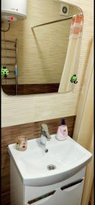 ein Badezimmer mit einem weißen Waschbecken und einem Spiegel in der Unterkunft Gagarina Naberegnaya in Dnipro
