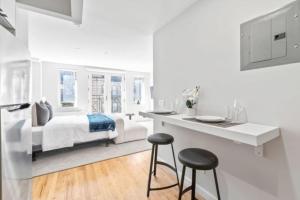 um quarto branco com uma cama e 2 bancos em Luxe Studio with Charming Juliet Balcony em Nova York