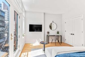 a white bedroom with a bed and a desk at Studio w Charming Juliet Balcony in Upper East in New York
