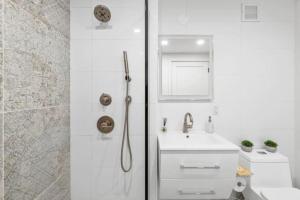 uma casa de banho branca com um chuveiro e um lavatório. em Luxe Studio with Charming Juliet Balcony em Nova York