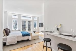 a white bedroom with a bed and two windows at Studio w Charming Juliet Balcony in Upper East in New York