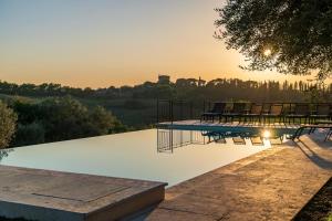 a pool with chairs and the sunset in the background at Palazzo Massaini - Le Scuderie in Pienza