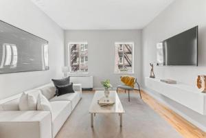a white living room with a white couch and a table at Top Notch 2BR in Upper East Mins to Central Park in New York