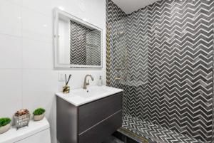 a bathroom with a sink and a checkered wall at Top Notch 2BR Suite Minutes to Central Park in New York