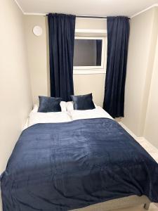 sypialnia z dużym łóżkiem z niebieską pościelą i oknem w obiekcie Tromsdalen Aurora Apartments w mieście Tromsø