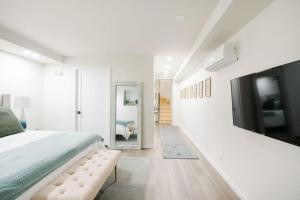 a white bedroom with a large bed and a tv at Luxury 2BR Duplex 5min to Central Park in New York