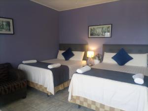 a bedroom with two beds and a chair at Hostal Vista del Mar in Trujillo