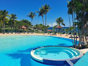 ein großer Pool mit Palmen in einem Resort in der Unterkunft Studio avec vue mer exceptionnelle, plage et piscine, Village Vacances Sainte-Anne in Sainte-Anne