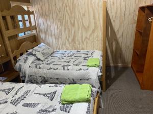 Dos camas en una habitación con toallas verdes. en Casa Chilhué - Hostal Residencial en Castro