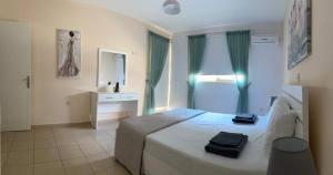 een slaapkamer met een bed, een wastafel en een spiegel bij Royal Seacrest Residence in Paphos City