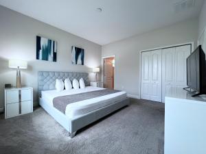 een witte slaapkamer met een bed en een flatscreen-tv bij Balmoral Resort-140AA in Haines City