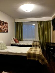 Hotelli Olla في Somero: غرفة نوم بسرير ونافذة مع ستائر خضراء
