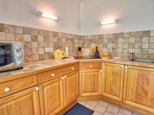 una cucina con armadi in legno e forno a microonde di Appartement cosy 3 pièces au pied des pistes, parking privé - FR-1-505-104 a Notre-Dame-de-Bellecombe