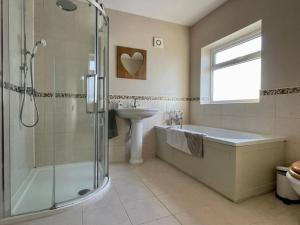 a bathroom with a shower and a tub and a sink at Scholes Park Drive, by the Seaside in Scalby