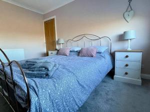 a bedroom with a bed with blue sheets and purple pillows at Scholes Park Drive, by the Seaside in Scalby