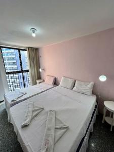 een slaapkamer met 2 bedden en een groot raam bij Flat Atlântico Neto in Fortaleza