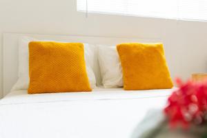 dos almohadas amarillas sentadas encima de un sofá blanco en Studio Apartment Volterra Curacao, en Willemstad