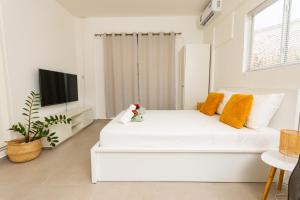 a white bedroom with a white bed and a tv at Studio Apartment Volterra Curacao in Willemstad