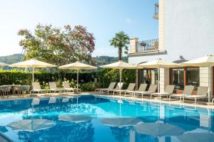 a swimming pool with chairs and umbrellas at Bellerive Lifestyle Hotel in Salò