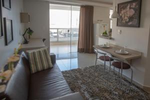 uma sala de estar com um sofá, uma mesa e uma cozinha em Flat inteiro Ônix Bueno em Goiânia