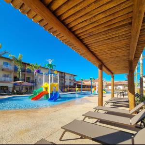 a swimming pool with chairs and a playground at Resort Ondas Praia in Porto Seguro