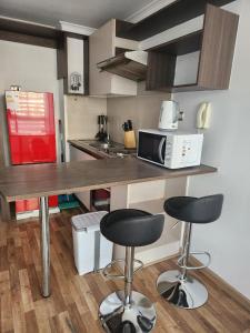 a kitchen with two bar stools and a microwave at Gamero a Pasos de Metro Hospitales in Santiago
