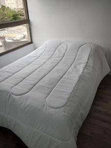 a white bed in a room with a window at Gamero a Pasos de Metro Hospitales in Santiago