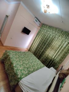 a small bedroom with a bed with a green blanket at Hotel Zavq in Andijan