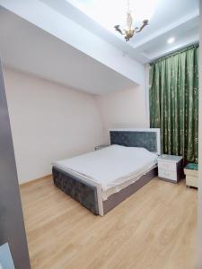 a bedroom with a bed and a green curtain at Hotel Zavq in Andijan