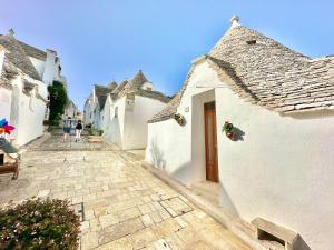 grupa białych budynków z brukowaną ulicą w obiekcie Trulli Fenice Alberobello w Alberobello