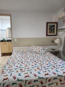 um quarto com uma cama com um edredão colorido em Flat em Boa Viagem - perto da praia no Recife