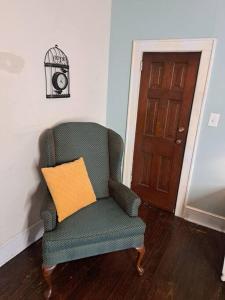 einem grünen Stuhl mit gelbem Kissen neben einer Tür in der Unterkunft Magnolia Place on Main in Florence