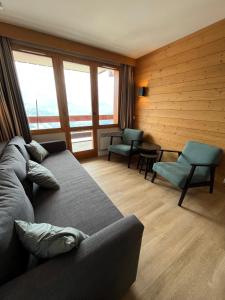 - un salon avec un canapé, des chaises et des fenêtres dans l'établissement Apartment Paradiski 309, à La Plagne Tarentaise