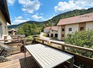een houten terras met een bank en een weg bij Entre Montagnes et Lacs in La Bresse