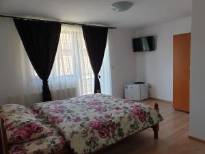 a bedroom with a bed with a floral bedspread and a window at Casa Luci&Matei in Căciulata