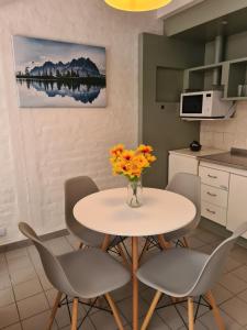 uma cozinha com uma mesa com cadeiras e um vaso de flores em Avellaneda Apart 3 em Mendoza
